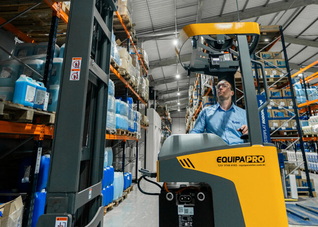 Operador sentado na empilhadeira retrátil EquipaPRO RTX2074 MAX em corredor de porta-palete